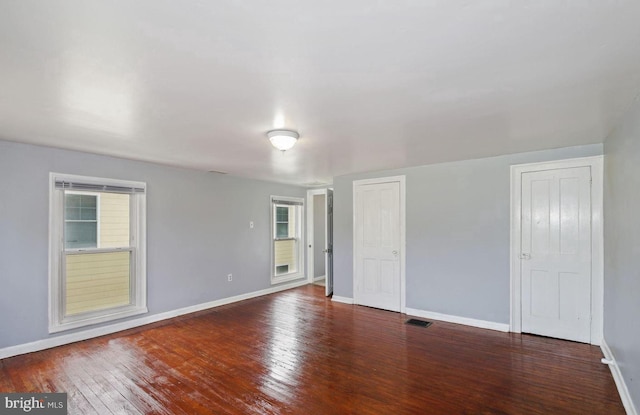 spare room featuring dark hardwood / wood-style floors and a healthy amount of sunlight