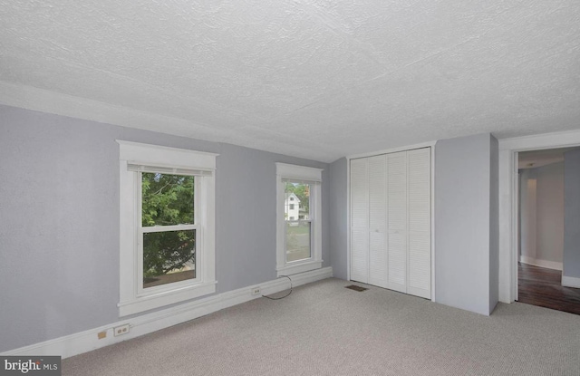 unfurnished bedroom featuring carpet floors, a textured ceiling, and a closet