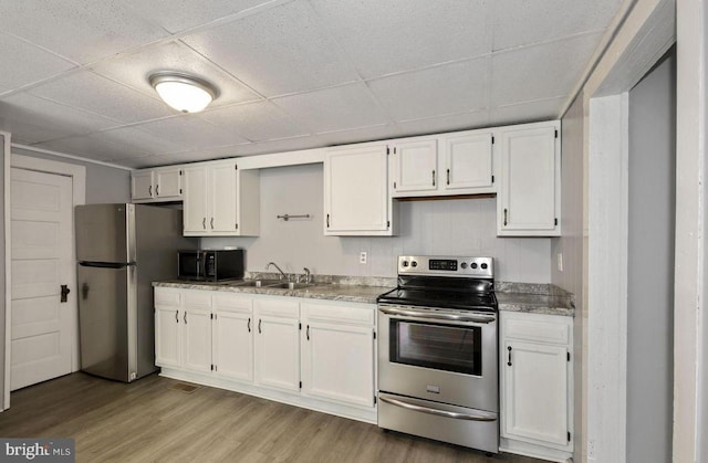 kitchen featuring appliances with stainless steel finishes, light wood-type flooring, sink, and white cabinets