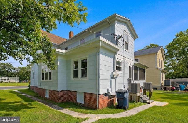 view of side of home with a lawn and central air condition unit