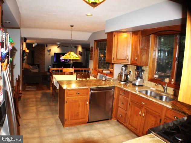 kitchen with decorative light fixtures, sink, dishwasher, kitchen peninsula, and backsplash