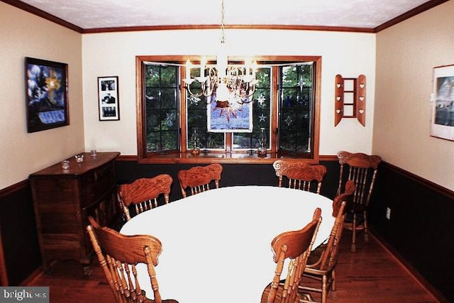 dining area with wood-type flooring, an inviting chandelier, and crown molding