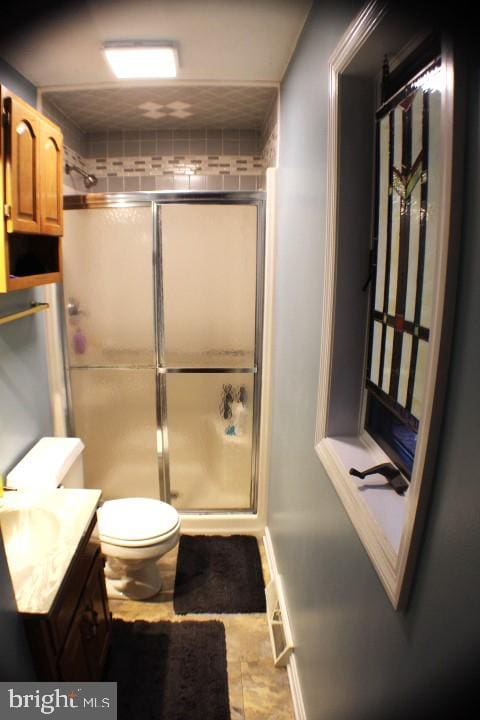 bathroom featuring tile patterned flooring, an enclosed shower, vanity, and toilet