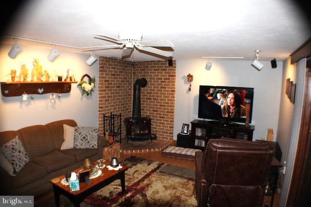 living room featuring wood-type flooring, ceiling fan, track lighting, and a wood stove