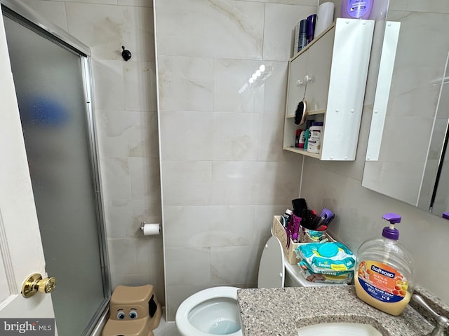 bathroom featuring tile walls, a shower with door, vanity, and toilet