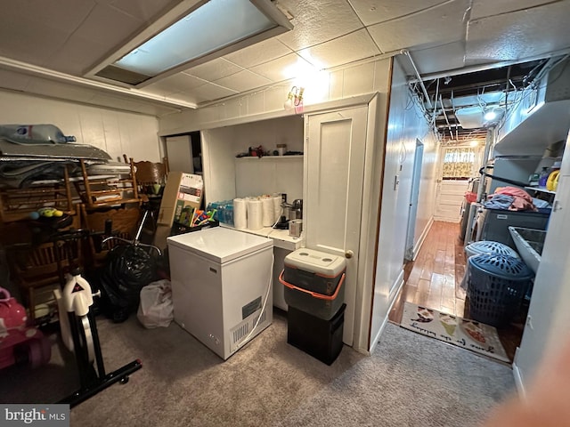 basement featuring wood-type flooring and refrigerator