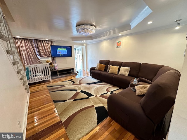 living room with a raised ceiling, hardwood / wood-style flooring, and crown molding