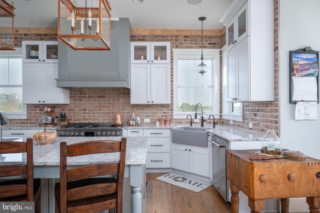 kitchen with hardwood / wood-style flooring, a kitchen breakfast bar, decorative light fixtures, white cabinets, and light stone counters