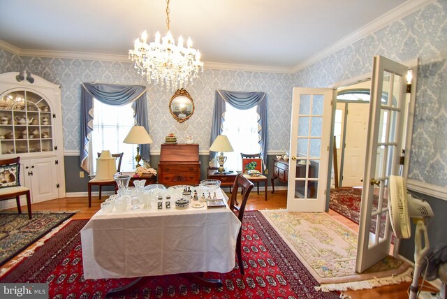 living area with an inviting chandelier, hardwood / wood-style flooring, crown molding, and french doors