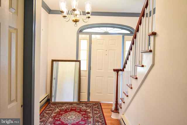 entrance foyer with baseboard heating, ornamental molding, an inviting chandelier, and hardwood / wood-style flooring