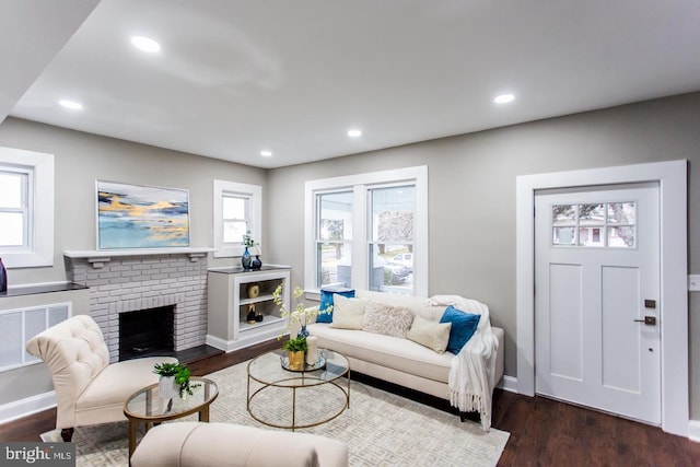 living room with a fireplace, plenty of natural light, and dark hardwood / wood-style flooring