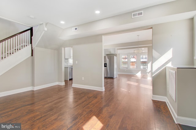 unfurnished living room with a notable chandelier and dark hardwood / wood-style flooring