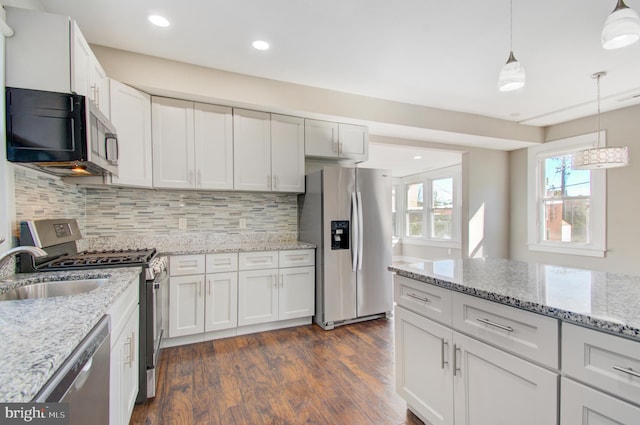 kitchen featuring tasteful backsplash, dark hardwood / wood-style floors, hanging light fixtures, white cabinets, and appliances with stainless steel finishes