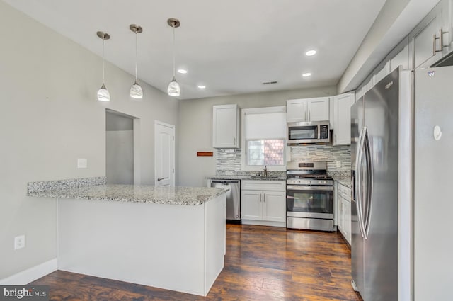 kitchen with white cabinets, appliances with stainless steel finishes, kitchen peninsula, and decorative light fixtures