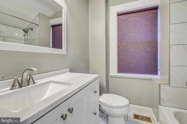 full bathroom with tiled shower / bath, vanity, and toilet