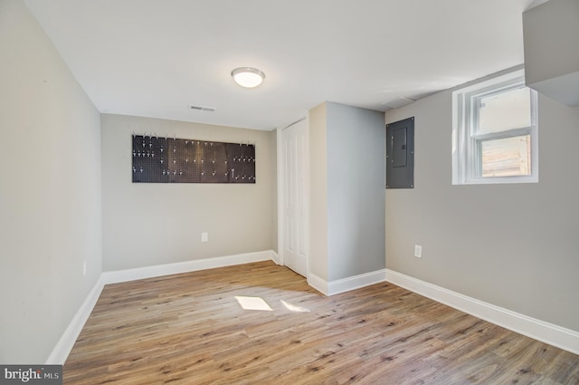 empty room featuring electric panel and light hardwood / wood-style flooring