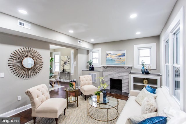 living room with a brick fireplace and hardwood / wood-style floors