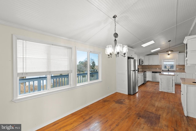 kitchen with white cabinetry, appliances with stainless steel finishes, lofted ceiling, and decorative light fixtures