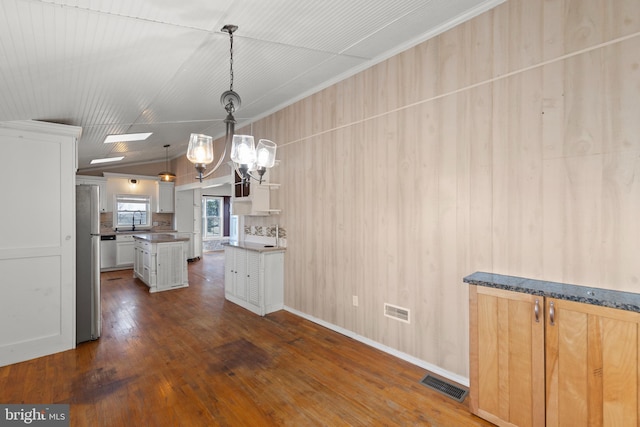 kitchen with lofted ceiling, dark hardwood / wood-style floors, stainless steel fridge, pendant lighting, and white cabinets