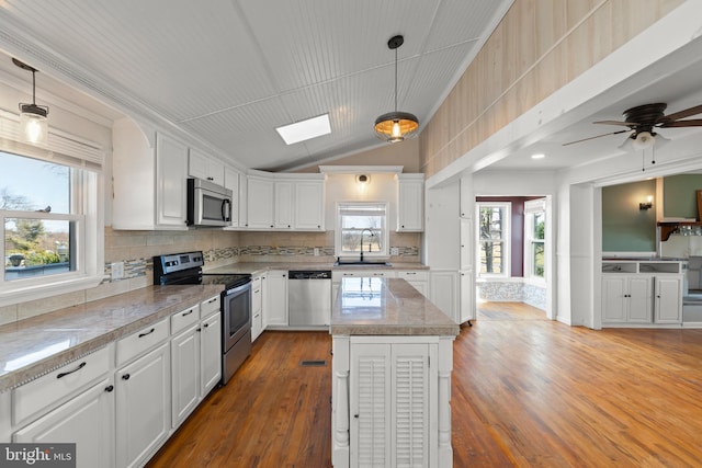 kitchen featuring white cabinetry, appliances with stainless steel finishes, a center island, and hanging light fixtures