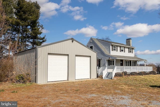 view of front facade with a porch, a garage, and an outbuilding