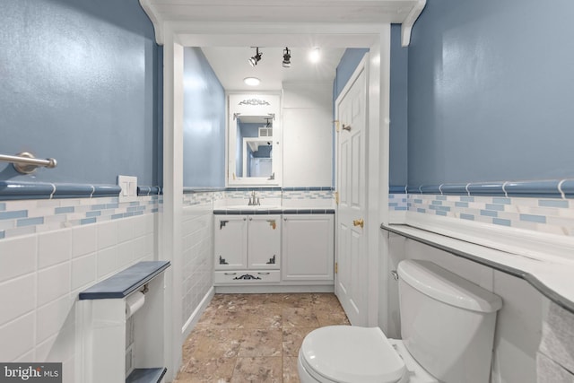 bathroom featuring vanity, toilet, and tile walls