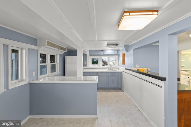 kitchen featuring sink, light tile patterned floors, gray cabinets, kitchen peninsula, and white fridge