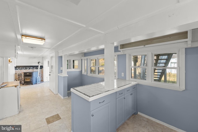 kitchen featuring tile counters, kitchen peninsula, and a wood stove