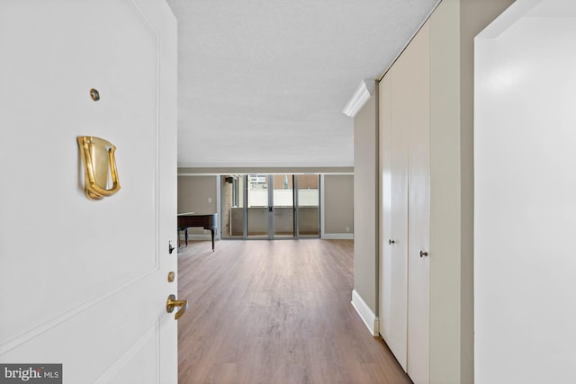 hallway with a textured ceiling, wood finished floors, and baseboards