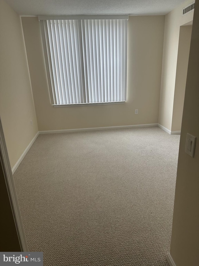 carpeted spare room with a textured ceiling