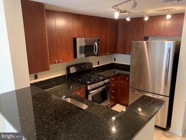 kitchen featuring dark stone countertops, light tile patterned floors, decorative light fixtures, kitchen peninsula, and stainless steel appliances