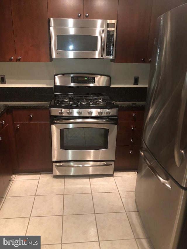 kitchen featuring dark brown cabinets, light tile patterned flooring, and stainless steel appliances