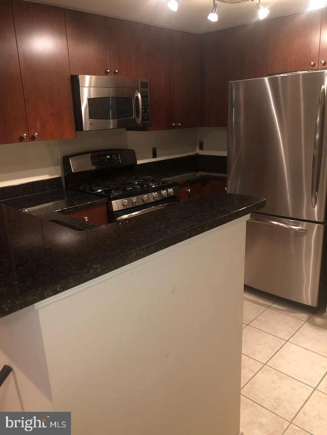 kitchen with dark stone countertops, light tile patterned floors, and appliances with stainless steel finishes