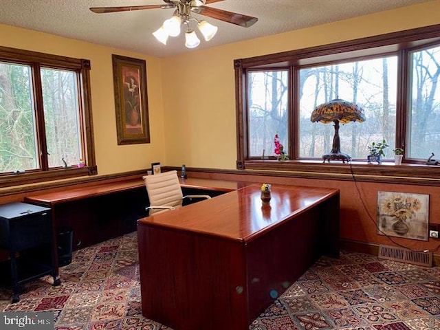 office featuring a textured ceiling, a healthy amount of sunlight, and ceiling fan