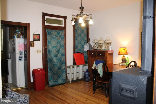 bedroom with radiator, a chandelier, white fridge, and dark hardwood / wood-style flooring