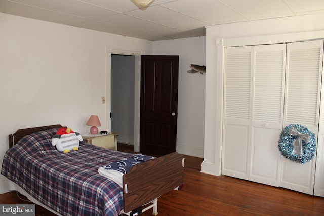 bedroom with dark hardwood / wood-style floors and a closet