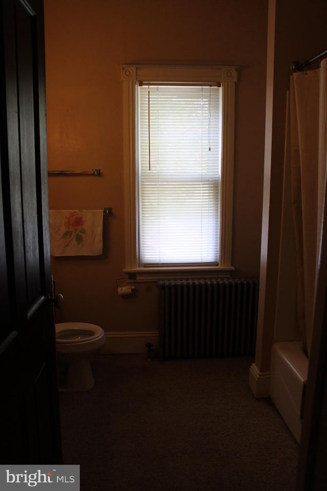 bathroom with radiator, toilet, and shower / bath combo