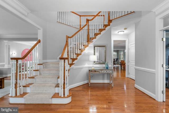 staircase featuring hardwood / wood-style flooring, crown molding, and baseboards