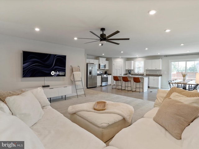 living room with light hardwood / wood-style floors, sink, and ceiling fan