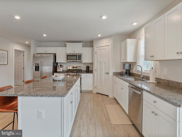 kitchen featuring a center island, sink, white cabinets, a kitchen bar, and stainless steel appliances