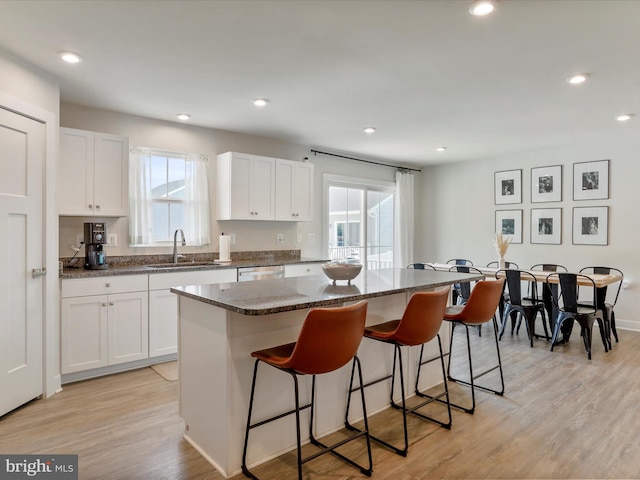 kitchen with a healthy amount of sunlight, white cabinetry, a center island, and sink