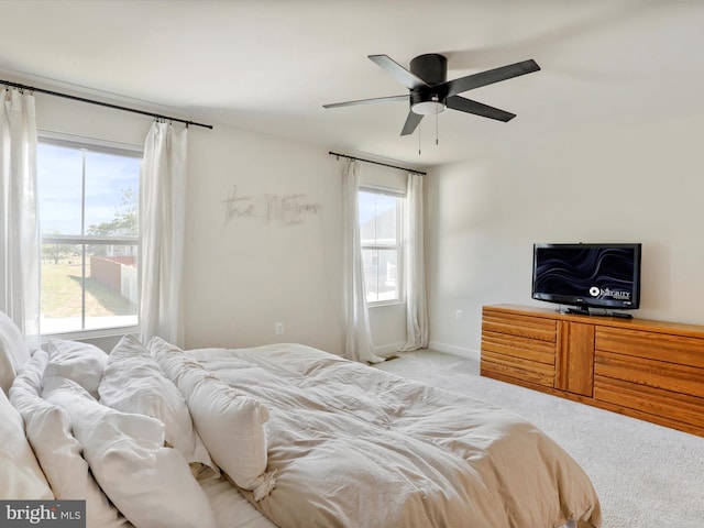 bedroom featuring light carpet, multiple windows, and ceiling fan