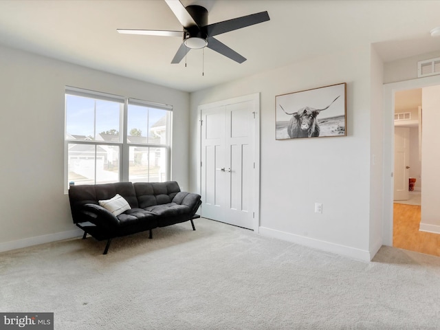 living area featuring light carpet and ceiling fan