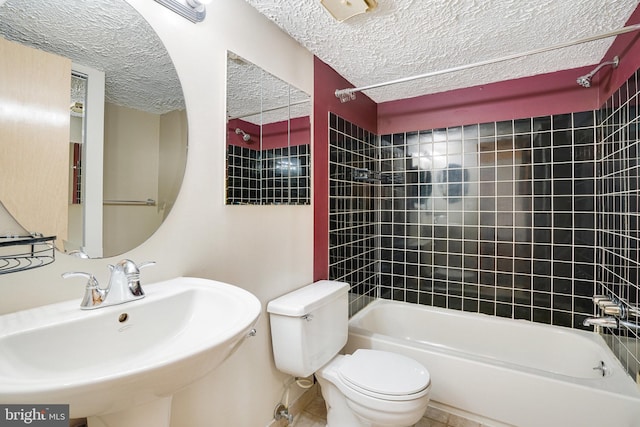 full bathroom featuring a textured ceiling, toilet, tiled shower / bath combo, sink, and tile patterned flooring