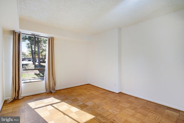 unfurnished room with light parquet flooring and a textured ceiling