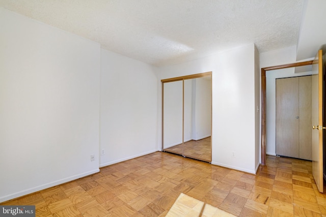 unfurnished bedroom with a closet, a textured ceiling, and light parquet floors