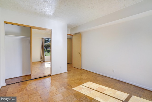 unfurnished bedroom featuring light parquet flooring, a textured ceiling, and a closet