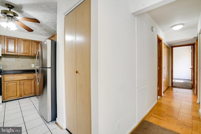 kitchen featuring stainless steel fridge, ceiling fan, light tile patterned floors, backsplash, and a textured ceiling