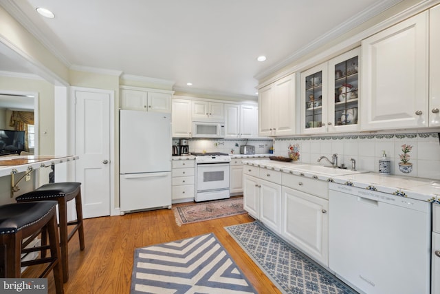 kitchen with light wood-type flooring, ornamental molding, white appliances, and white cabinetry