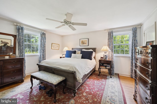 bedroom with multiple windows, hardwood / wood-style flooring, ceiling fan, and crown molding